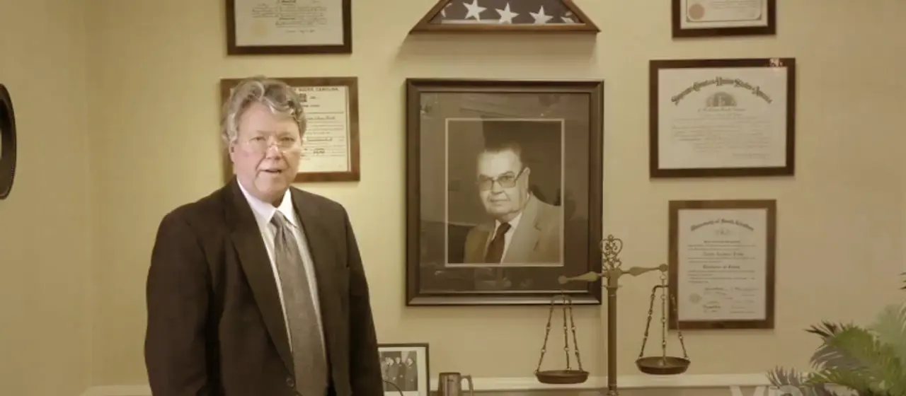 J. Calhoun Pruitt, Jr. in the firm's office beside a framed portrait and his law licenses
